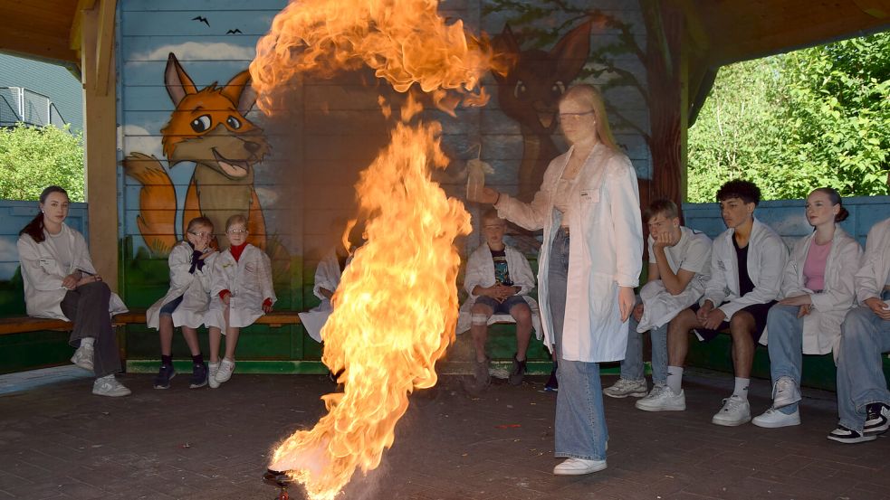 Lea Voss aus der neunten Klasse der Oberschule Uplengen zeigt den Schüler aus der Klasse 3a der Grundschule Lengenerland was passiert, wenn sie versucht, brennendes Öl mit Wasser zu löschen. Einige Spritzer genügen, und eine Stichflamme steigt hoch. Fotos: Zuidema