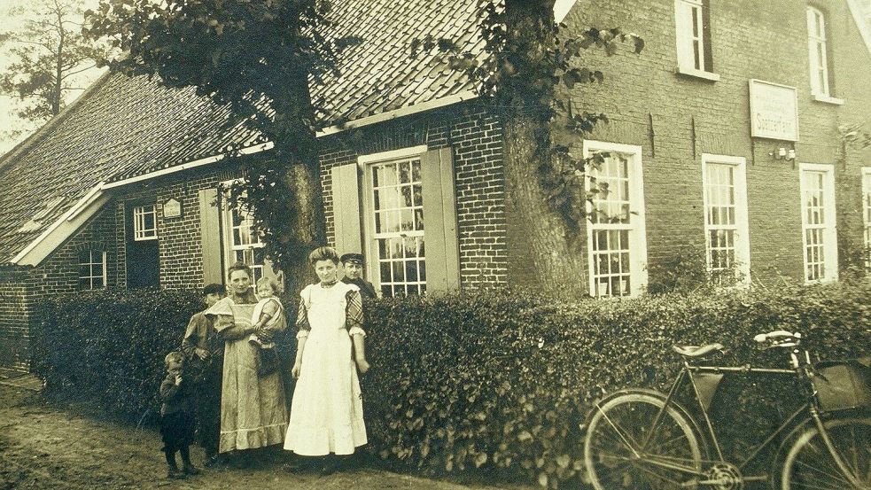 Ein Familienfoto aus dem Jahr 1910: Vor dem Haus der Familie Schoon in Spetzerfehn ist Greta Schoon noch als Kleinkind auf dem Arm ihrer Mutter. Ihr 15 Jahre älterer Onkel Johann Schoon steht ganz rechts, hinter der Hecke. Foto: Archiv Wojak