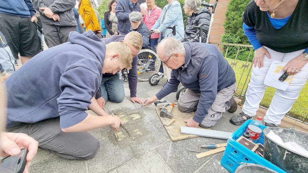 Bruin Boerema (rechts) verlegte zusammen mit Schülern der BBS II in Leer die Stolpersteine an der Hohen Loga 34. Im Hintergrund schaut Albrecht Weinberg, Ehrenbürger der Stadt und Holocaust-Überlebender, aufmerksam zu. Foto: Bothe