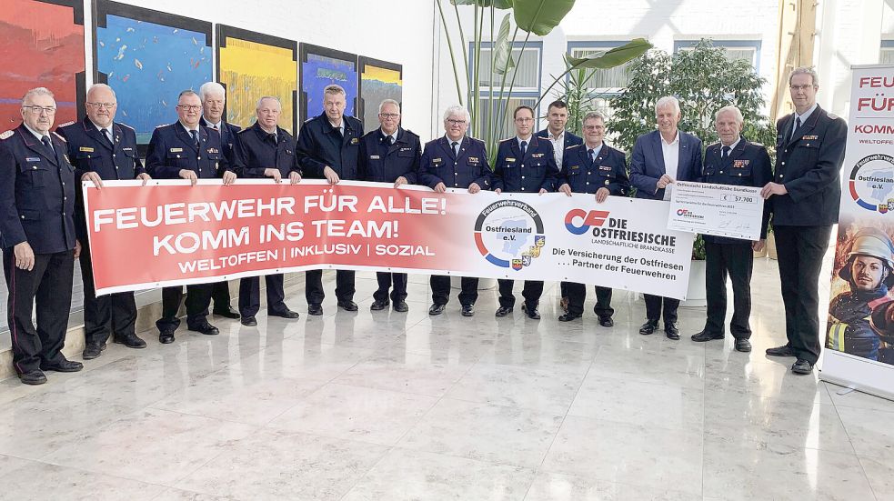 Die ostfriesischen Feuerwehr-Führungskräfte und Brandkassen-Vertreter präsentieren auf Banner und Plakat, wofür sie gemeinsam stehen (von links): Arnold Eyhusen, Jochen Behrends, Erwin Reiners, Karl Töpfer, Bernd Lenz, Ernst Berends, Ernst Lübben, Friedhelm Tannen, Mario Eilers, Gerrit Wilken (Brandkasse), Dieter Helmers, Thomas Weiss (Brandkasse), Ernst Hemmen und Gerd Diekena. Foto: Privat