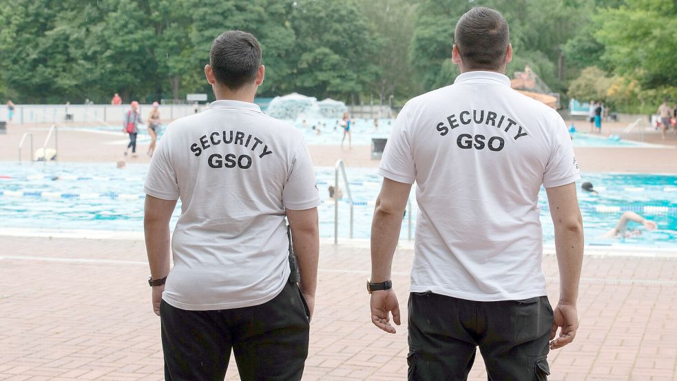 Mitarbeiter eines Sicherheitsdienstes stehen am Beckenrand. Das Auricher Schwimmbad De Baalje setzt nach Angriffen auf Mitarbeiter auf mehr Sicherheit. Symbolfoto: Zinken/DPA