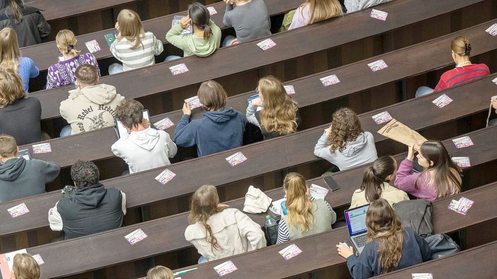 Studenten nehmen an der Einführungveranstaltung im Audimax der Ludwig-Maximilians-Universität teil. Foto: Peter Kneffel/dpa