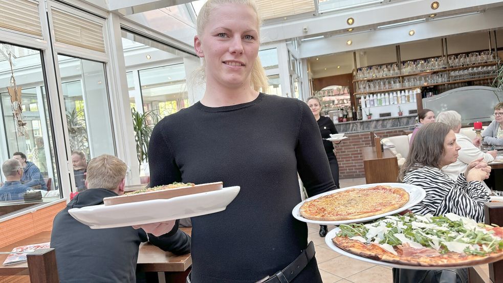 Elke Chander bringt das Essen: In der linken Hand hat sie zwei verschiedene Pizzen – hinten die Tradizionale und vorne die italiensiche Art. Fotos: Hellmers