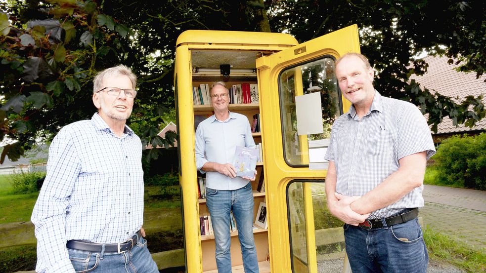 Der Arbeitskreis Uns Dörp Tergast – hier Hermann Hellmers (von links), Thomas Bona und Fokko Böden – hat einen Bücherschrank in einer Telefonzelle eingerichtet. Foto: Lüppen