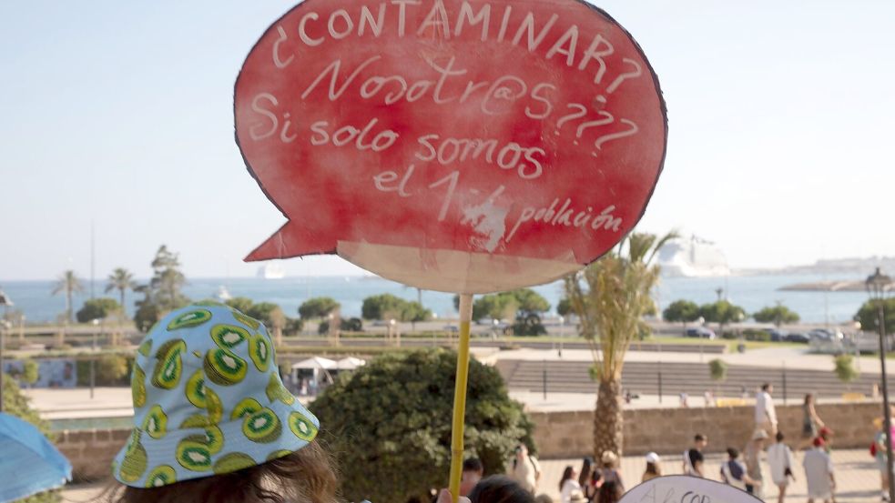 Einheimische auf Mallorca halten ein Schild, auf dem steht: „Verschmutzen? Wir??? Wo wir nur 1,2 (Millionen) Einwohner sind.“ Foto: Clara Margais/dpa