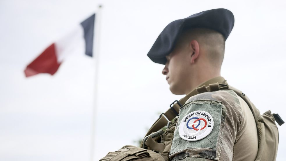 Wachposten unter der Flagge: einer von Tausenden Soldaten, die die Olympischen Spielen in Paris absichern. Foto: picture alliance/AP/Thomas Padilla