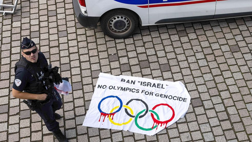 Ein französischer Polizist steht neben einem auf dem Boden liegenden Plakat mit der Aufschrift „Ban „Israel No Olympics For Genocide“, das während eines Laufs mit dem Olympischen Feuer durch Huningue konfisziert wurde. Foto: dpa/Philipp von Ditfurth