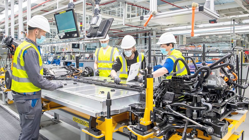 Volkswagen-Arbeiter stehen im VW-Werk Emden um den Akku-Block eines ID.4. In dem ostfriesischen Werk werden E-Autos gebaut, aber keine Akkus selbst hergestellt. Foto: dpa/Sina Schuldt