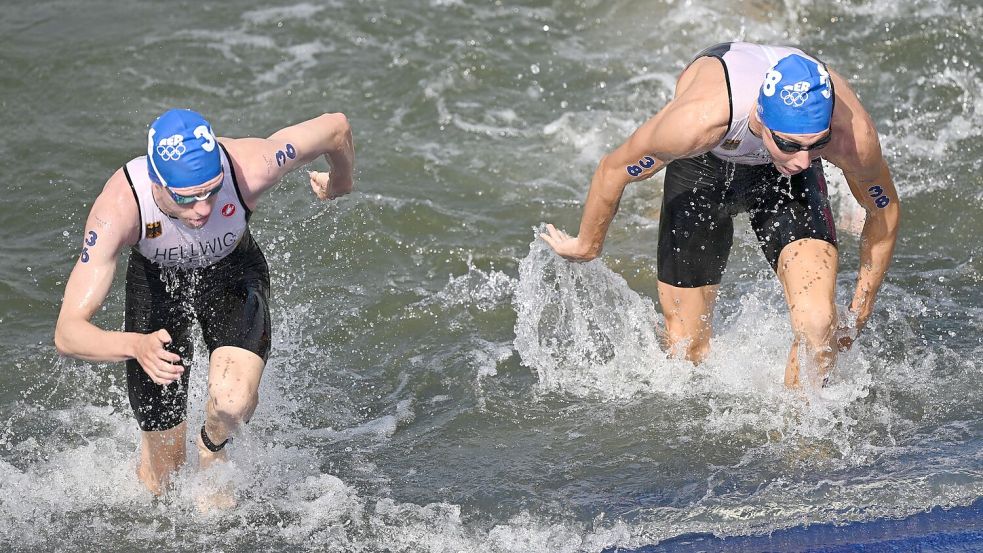 Tim Hellwig und Jonas Schomburg steigen aus der trüben Seine. Foto: Marijan Murat/dpa