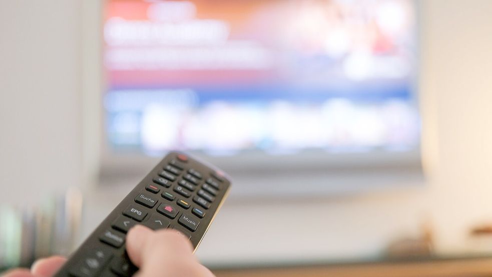 Eine Hand bedient eine Fernbedienung für ein TV-Gerät. Foto: Bernd Weißbrod/dpa