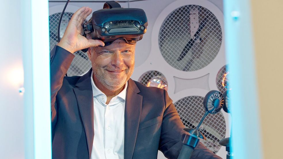 Wirtschaftsminister Robert Habeck (Grüne) steht bei einem Messerundgang bei der Computerspiele-Messe Gamescom 2022 in einem Simulator und trägt dabei eine Virtual-Reality-Brille. Foto: Henning Kaiser/dpa