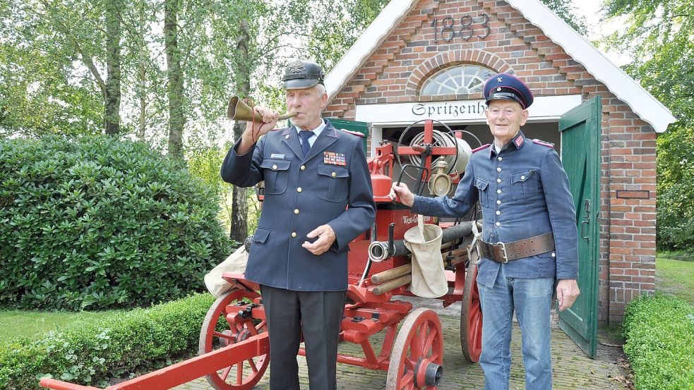 Ernst Hemmen (links, mit dem Feuerhorn) und Klaus de Wall sind in der Altersabteilung der Freiwilligen Feuerwehr West-Mittegroßefehn/Ulbargen aktiv und kümmern sich um die historische Handdruckspritze. Beide bringen es zusammen auf 124 Jahre geballte Feuerwehrkompetenz. Foto: Ullrich