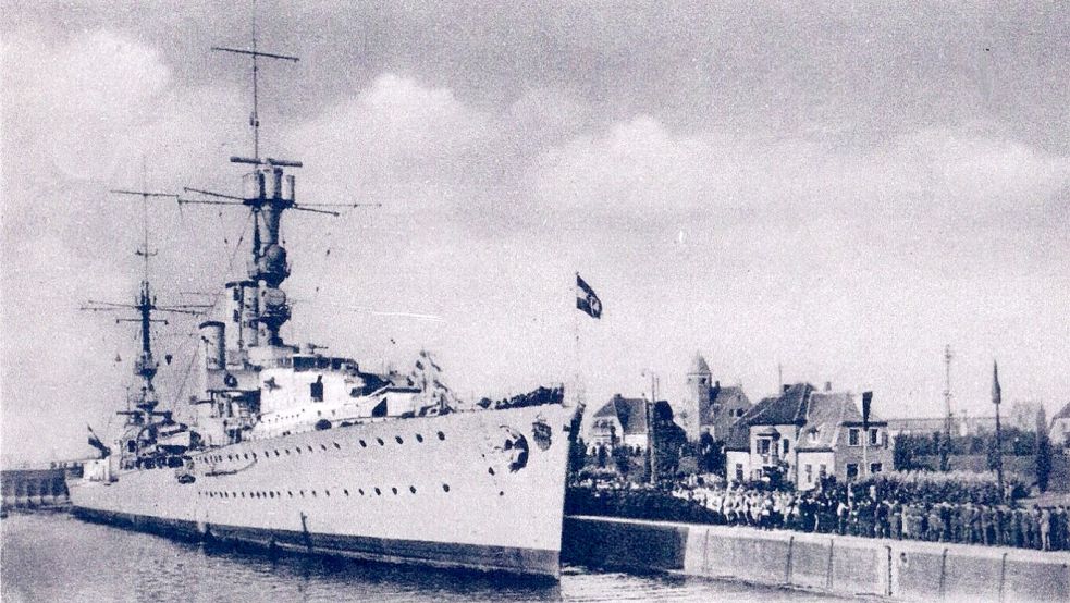 Der Leichte Kreuzer „Emden“ legte am 29. Oktober 1934 an der Großen Seeschleuse in Emden anlässlich der Einweihung der „Emden-Tafel“ an der Wache am Rathausplatz an. Das Schiff wird auf dem Foto von den Angehörigen der VI. Ersatz-Marine-Artillerie-Abteilung begrüßt. Im Hintergrund der Turm des Lotsenhauses sowie das Dach des Getreideschuppens der Fa. Bley auf der Westseite des Außenhafens. Foto: Postkarte aus dem Archiv der Stiftung Johannes-a-Lasco-Bibliothek