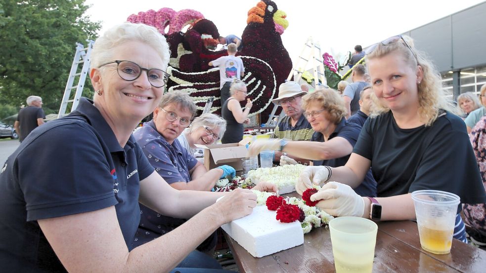 Von Krisen-Stimmung keine Spur: Karina Dierks (links) und Sabrina Geil-Alting (rechts) stecken mit Sängerinnen und Sängern des Chors TonArt, Freunden und Verwandten den Birkhahn-Wagen. Foto: Böning