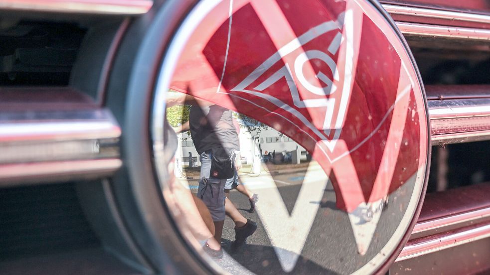 Eine Fahne der IG Metall spiegelt sich in einem VW Logo. Belegschaft und Gewerkschaft positionieren sich gegen die Sparpläne des Vorstands. Foto: Schmidt/DPA