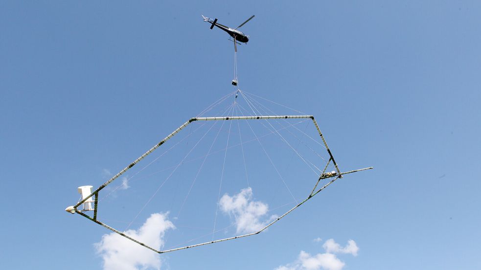 Ein Hubschrauber zieht in circa 30 Metern Höhe die riesige Antenne. Dieses Bild wird schon bald in der Region zu sehen sein. Foto: LBEG/Eike Bruns