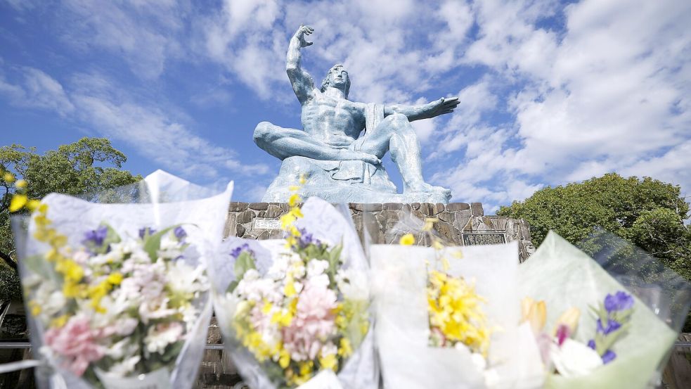 Blumensträuße liegen vor der Friedensstatue im Friedenspark in Nagasaki, im Südwesten Japans. Die japanische Organisation Nihon Hidankyo von Überlebenden der Atomwaffenabwürfe auf die Städte Hiroshima und Nagasaki wird in diesem Jahr mit dem Friedensnobelpreis geehrt, wie das norwegische Nobelkomitee in Oslo bekanntgab. Foto: dpa/kyodo