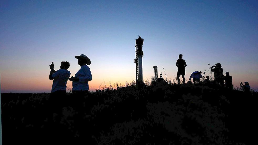 Menschen fotografieren den Sonnenuntergang hinter der Rakete Starship von SpaceX. Foto: Eric Gay/AP