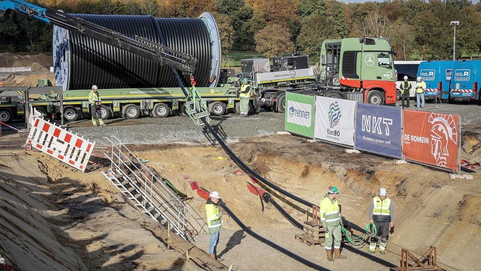 Das Erdkabel wird mit einem Schwertransporter geliefert und mit Hilfe einer Seilwinde in den Graben gehoben. Foto: Focke Strangmann/dpa