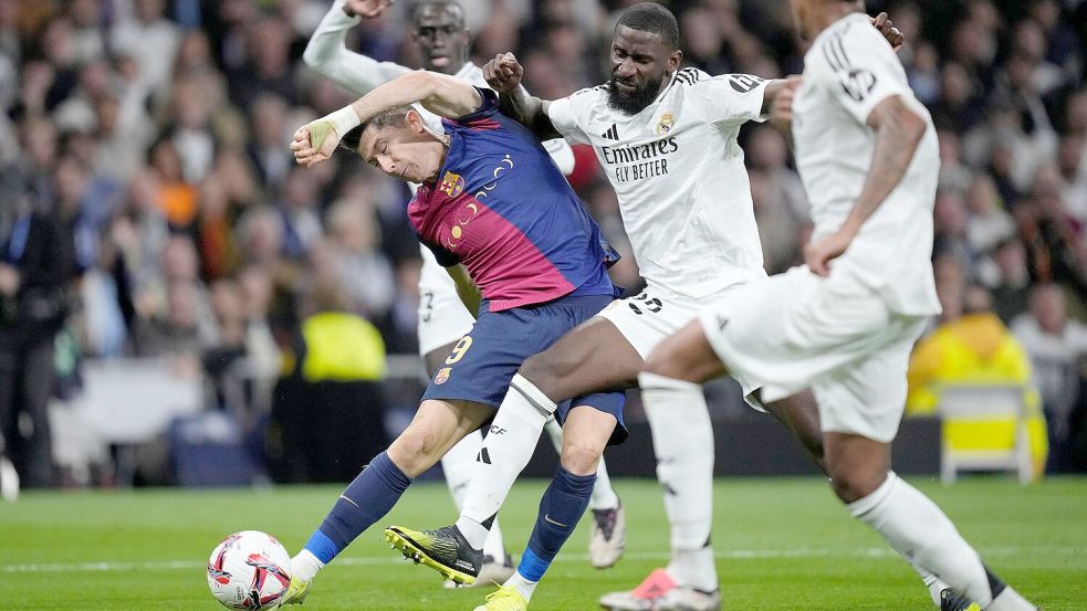 Barcelonas Robert Lewandowski leitet das Debakel für Real Madrid ein. Antonio Rüdiger (M) erlebt einen bitteren Abend. Foto: Bernat Armangue/AP