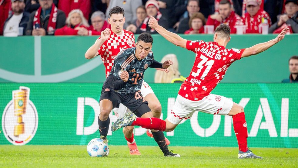 Jamal Musiala, hier beim Pokalspiel in Mainz, ist von den Gegenspielern kaum mit fairen Mitteln vom Ball zu trennen. Foto: Torsten Silz/dpa