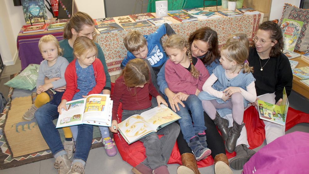 Kinder und Mütter haben sich in eine Leseecke zurückgezogen und schmökern auf der Buchmesse gemeinsam in neuen Kinderbüchern. Foto: Niet