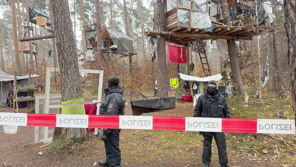 Polizeikräfte sichern das Waldgebiet hinter einer Absperrung. Umweltaktivisten, die gegen Tesla protestieren, müssen ihr Camp räumen. Foto: Lutz Deckwerth/dpa