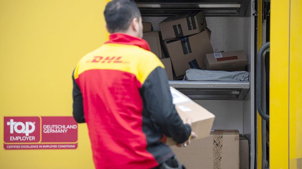 Ein Post-Mitarbeiter trägt ein Paket in einen Lieferwagen. Foto: Hannes P. Albert/dpa