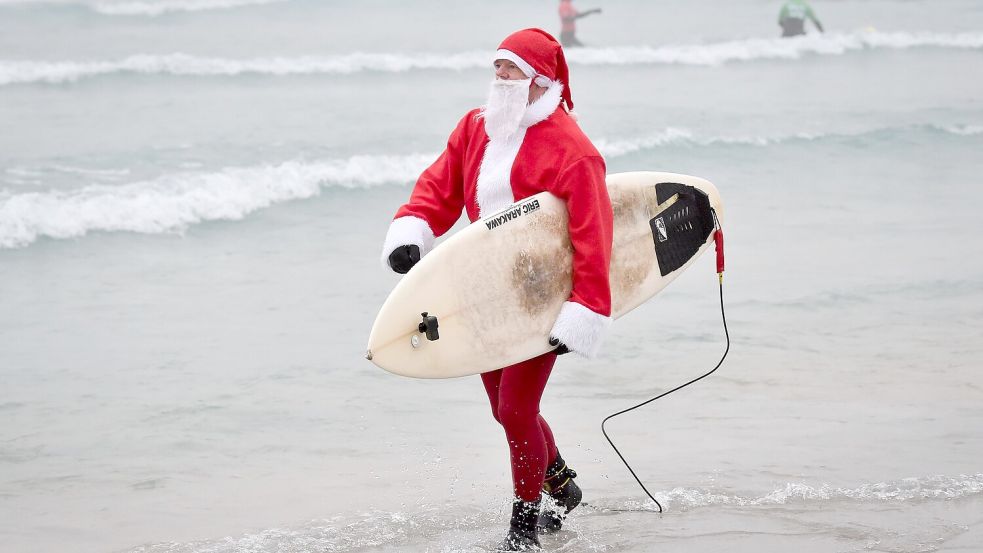 Events mit surfenden Weihnachtsmännern gibt es mittlerweile in mehreren Ländern. (Archivbild) Foto: Ben Birchall/PA Wire/dpa