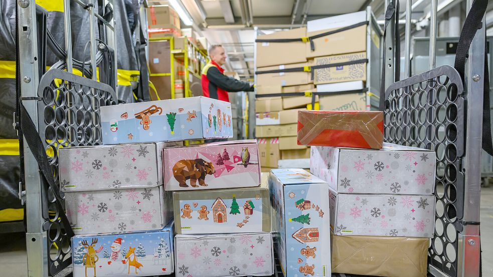 Ein Transportwagen voller Päckchen und Paketen mit Weihnachtsmotiv steht im Paketzentrum. Vor Heiligabend sollen sie beim Empfänger ankommen. Foto: dpa/Patrick Pleul