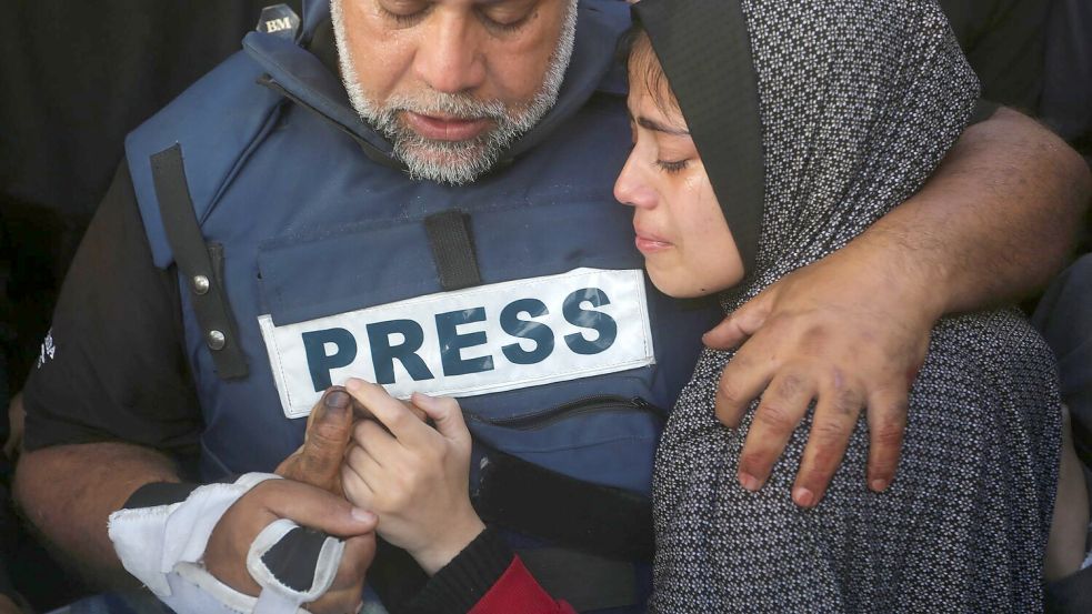 Der Al-Dschasira-Journalist Wael al-Dahdu hält die Hand seines Sohns Hamza, der ebenfalls für Al-Dschasira arbeitete und bei einem israelischen Luftangriff im Gazastreifen getötet wurde. Foto: Hatem Ali/AP/dpa