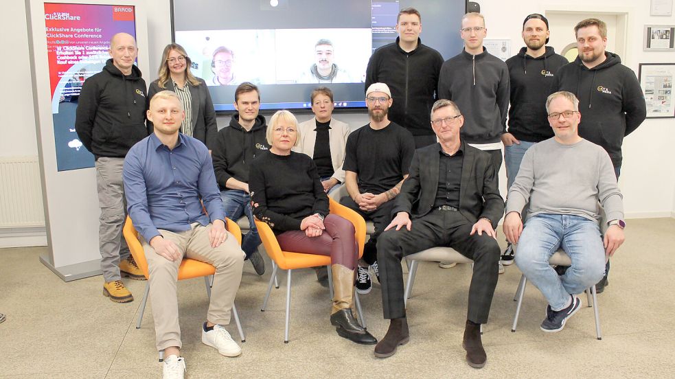 Das Team von „LS IT & Media“: Eike Groen (sitzend von links), Daniel Peschel, Annemarie Groen, Brigitte Stawarczyk, Ralf Watermann, Eckhard Groen, Hans-Jürgen Schüürmann sowie Ilia Tkalenko (stehend von links), Martha Deeke, Jan Stöhr, Tim Müller, Hendrik Saathoff und Keno Debelts. Auf dem Bildschirm sind Janek Grafenburg (links) und Anton Strodthoff zu sehen. Foto: Walker