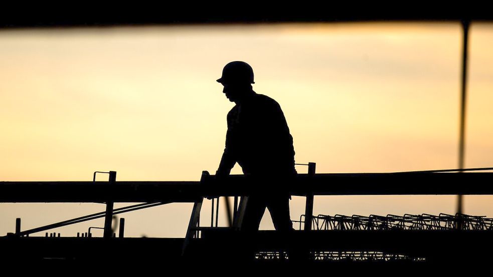 Ein Bauarbeiter in der Morgendämmerung. Laut Ifo-Beschäftigungsbarometer wollen viele Unternehmen Personal abbauen, in der Baubranche zeichnet sich jedoch keine größere Entlassungswelle ab. Foto: Julian Stratenschulte/dpa