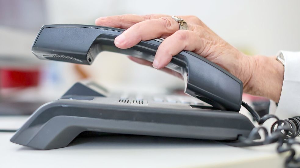 Eine Frau nimmt einen Telefonhörer in die Hand. Foto: Jan Woitas/dpa