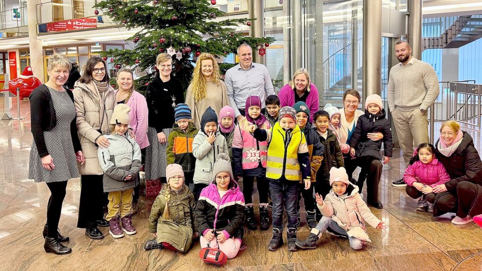 Rund 20 Kinder der katholischen Kindertagesstätte St. Ludgerus Aurich sangen zum Dank für die finanzielle Unterstützung „In der Weihnachtsbäckerei“ und rührten damit gleichermaßen Sparkassenmitarbeiter wie Kunden. Die Spende nahm Kita-Leiterin Martina Hardy (hintere Reihe, 5. von links) entgegen. Foto: privat