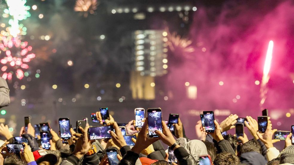 Silvester in Düsseldorf - und Tausende Menschen am Rheinufer filmen mit. Foto: Christoph Reichwein/dpa