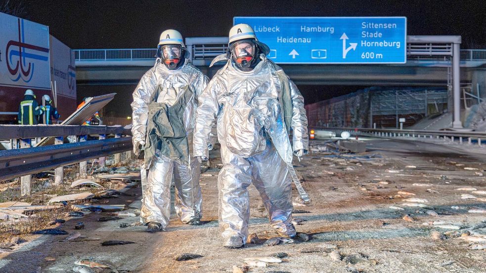 Überall Fische auf der Fahrbahn: Bei dem Unfall auf der A1 mussten Feuerwehrleute die Unfallstelle zunächst in speziellen Schutzanzügen sichern. Foto: JOTO/dpa