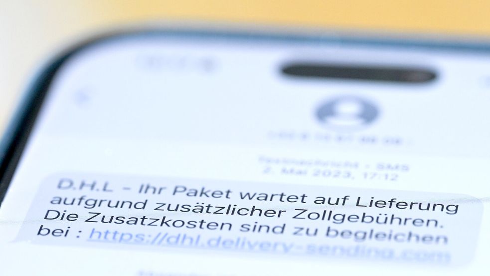 Auf einem Smartphone ist eine Betrugs-SMS zu lesen, in der Kriminelle ein Paket ankündigen und dafür Zollgebühren einfordern. Foto: Wolf von Dewitz/dpa