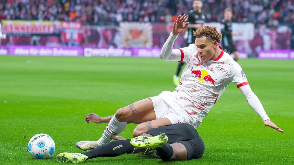 Leipzigs Antonio Nusa geht im Zweikampf mit Derrick Köhn zu Boden. Foto: Jan Woitas/dpa