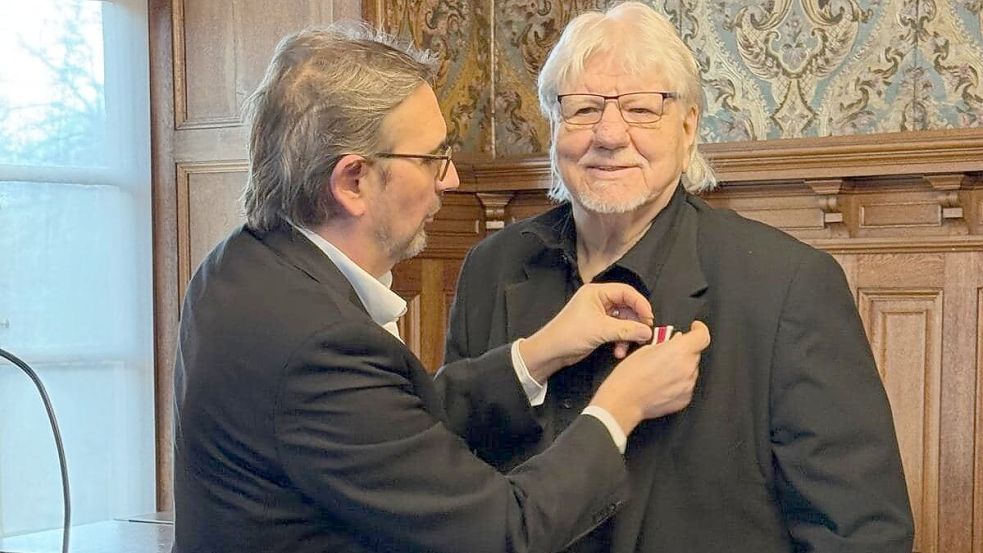 Frieslands Landrat Sven Ambrosy heftet Gerd Brandt (rechts) den Verdienstorden an. Foto: Landkreis Friesland