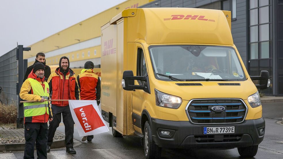 Post-Mitarbeiter am Werkstor, aber nicht auf dem Werktor. Der Grund: Sie sind im Warnstreik. Foto: Oliver Berg/dpa