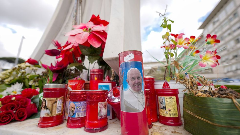 Vor dem Gemelli-Krankenhaus im Rom sind für den erkrankten Papst Franziskus Kerzen aufgestellt. Foto: Andrew Medichini/AP/dpa