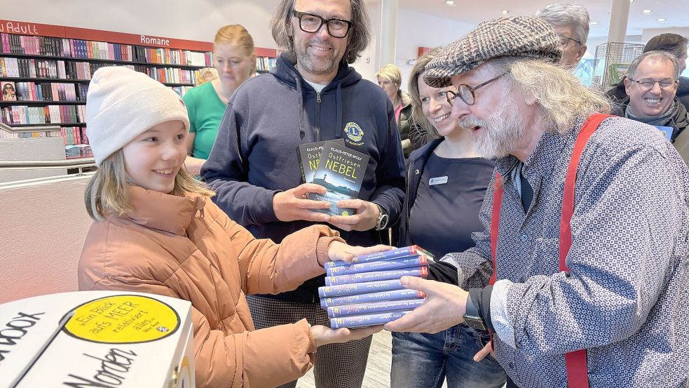 Johanna ließ sich gleich einen ganzen Stapel Bücher einer Jugend-Krimireihe von Klaus-Peter Wolf signieren. Achim Freimuth (2. von links) und Nicole Stürenburg vom Lions Club Aurich Aurora freuten sich über den Einsatz des Autors für den guten Zweck. Foto: Christin Wetzel