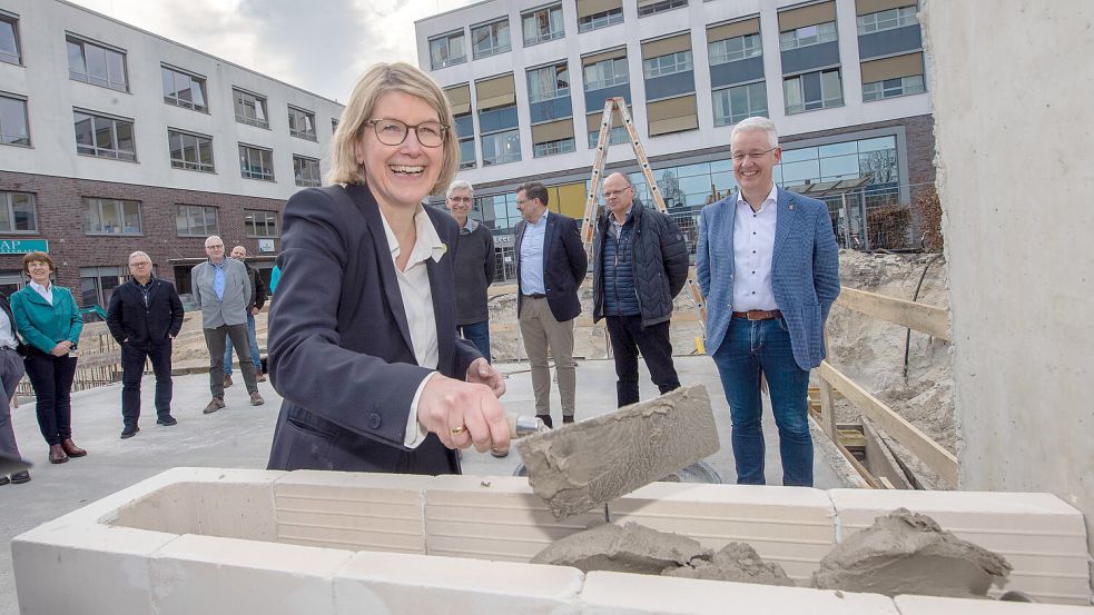 Klinikum-Geschäftsführerin Daniela Kamp mauerte unter den aufmerksamen Blicken der Gäste – darunter Aufsichtsratsvorsitzender, Landrat Matthias Groote (von rechts), Bauunternehmer Helmut Hockmann, den Architekten Thomas Rettig und Torsten Schmidt sowie der Ärztlichen Direktorin, Dr. Sylvia Kotterba (von links) und dem ehemaligen Klinikum-Geschäftsführer Holger Glienke – die Zeitkapsel ein. Foto: Ortgies